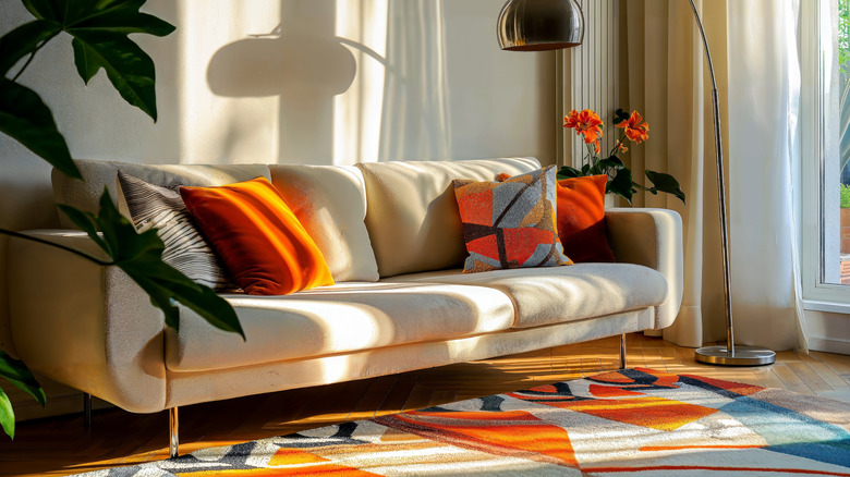White sofa with colorful throw pillows and colorful rug in front.