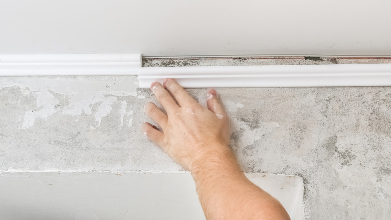 person installing plastic coving on ceiling