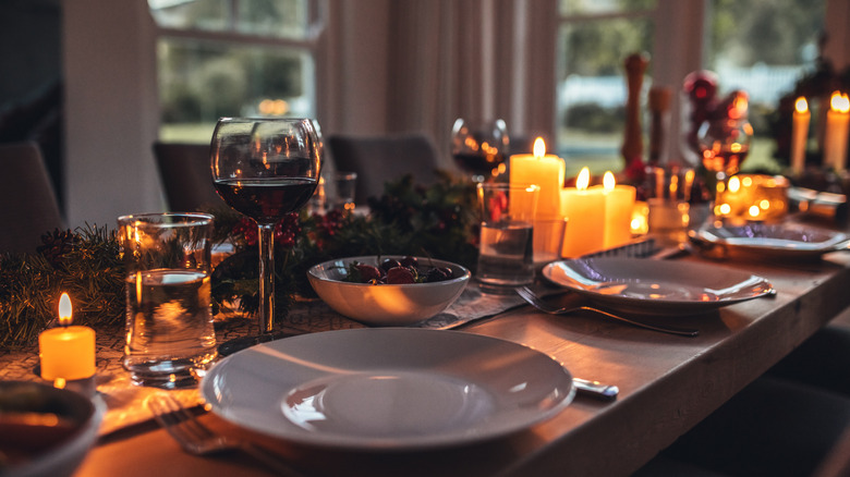 Thanksgiving tablescape with candles, plates, and glasses of wine