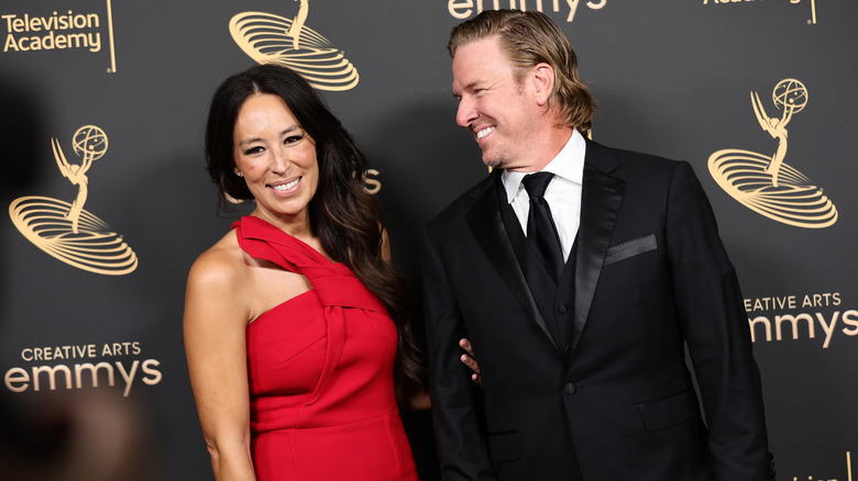 Joanna Gaines and her husband stand against a photo backdrop at the Emmy awards.