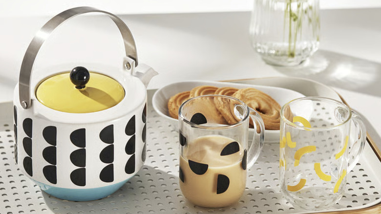 Product image of SKEDSTOR teapot, with metal handle, yellow lid, and white base with black geometric shapes.