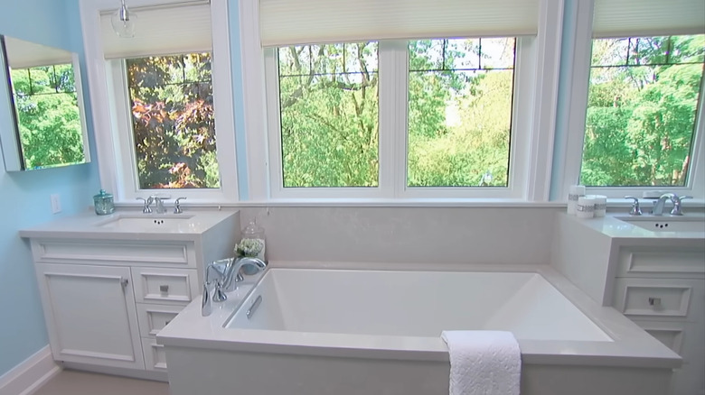 A bathroom with a bathtub in between two vanities