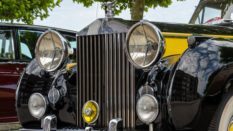 A yellow on black 1955 Rolls-Royce sedan with large headlights