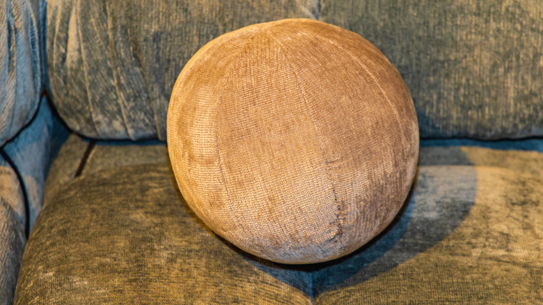 Brown ball-shaped pillow on grey sofa