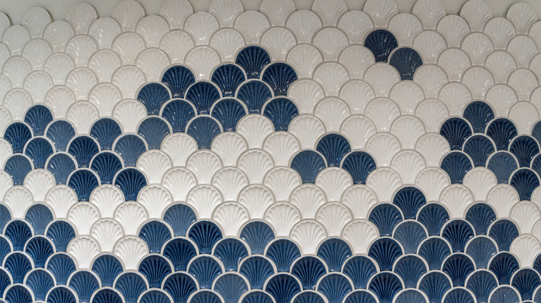 A wall with a haphazard pattern of blue and white ceramic fish-scale tiles.