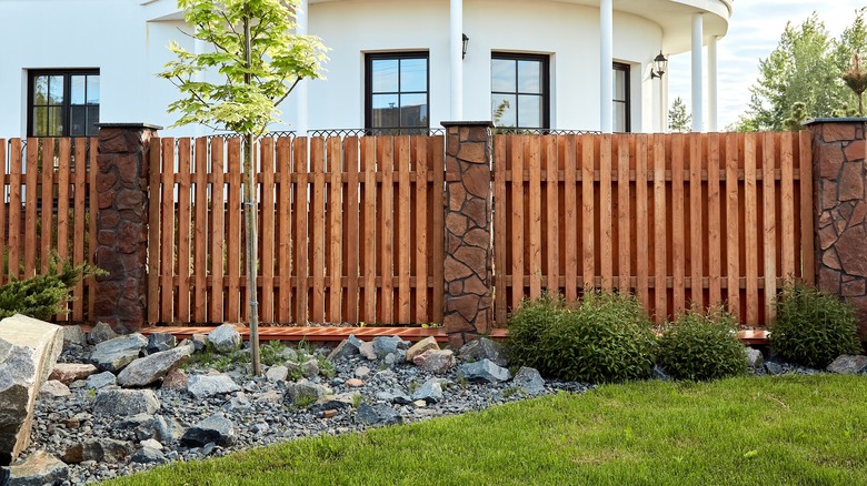 Wood fence with stone pillars outside white house