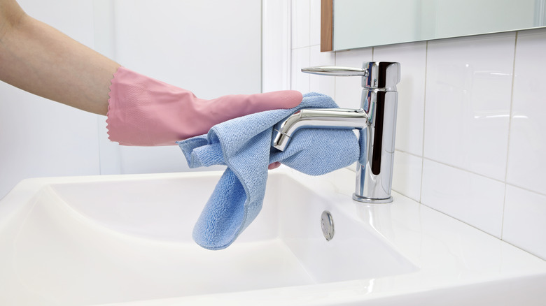 Person with gloves wiping faucet