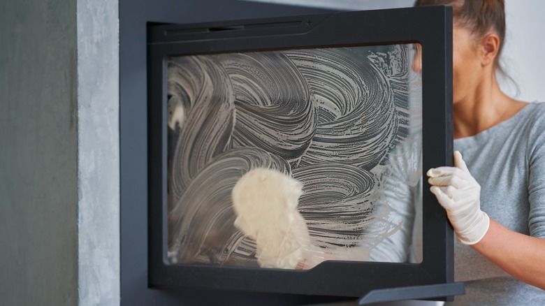 Person cleaning fireplace door