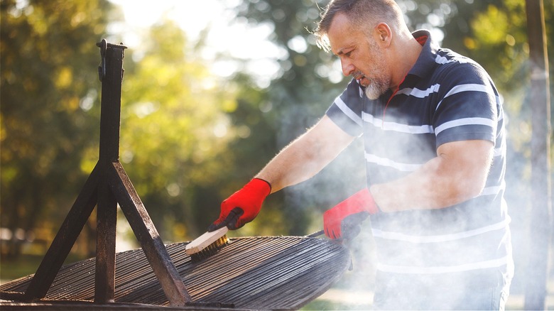 man cleaning grill grate