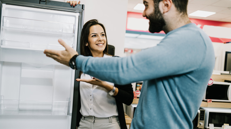 A couple is looking at a refrigerator in a store