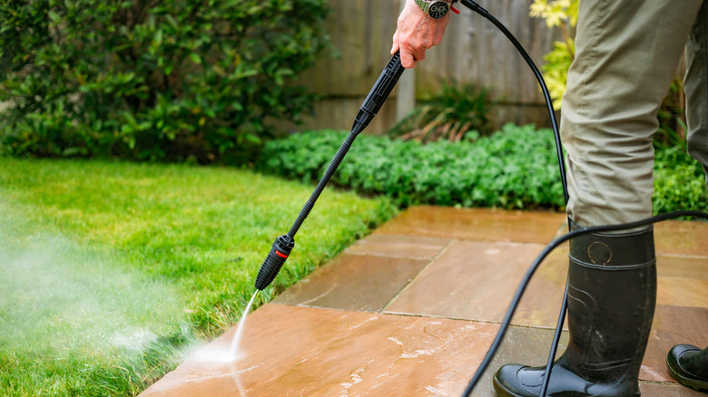 A man cleans pavers with a pressure washer