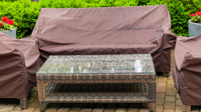 Outdoor furniture covered in waterproof protectors with coffee table exposed to rain
