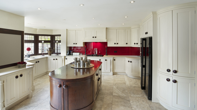 A kitchen with round brown island and white cabinets with curved accents