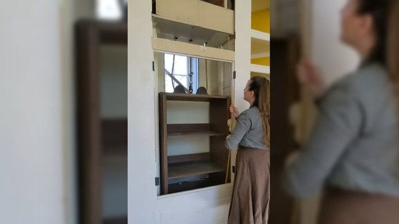 Person hoisting antique dumbwaiter