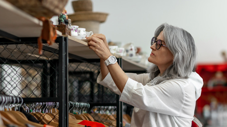 A woman examining a teacup in a secondhand store