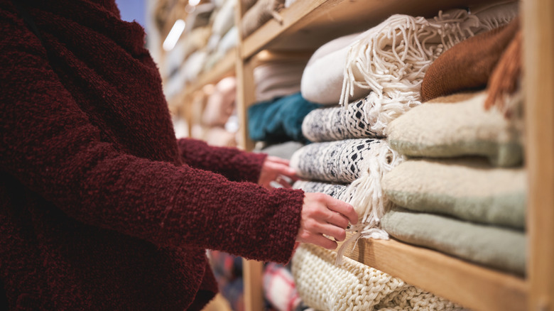A person browsing the selection of folded blankets in a store