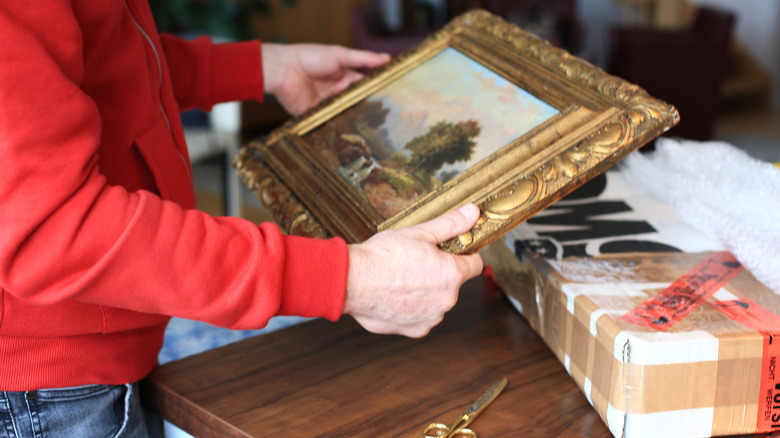 Man holds painting of a landscape