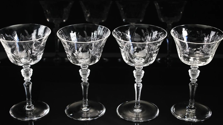 Four etched glass Champagne coupes in a row.