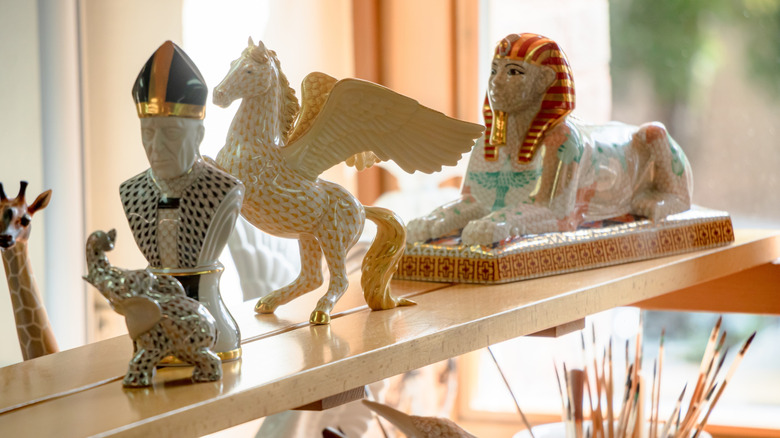 Herend figurines painted and decorated in gold on a shelf.