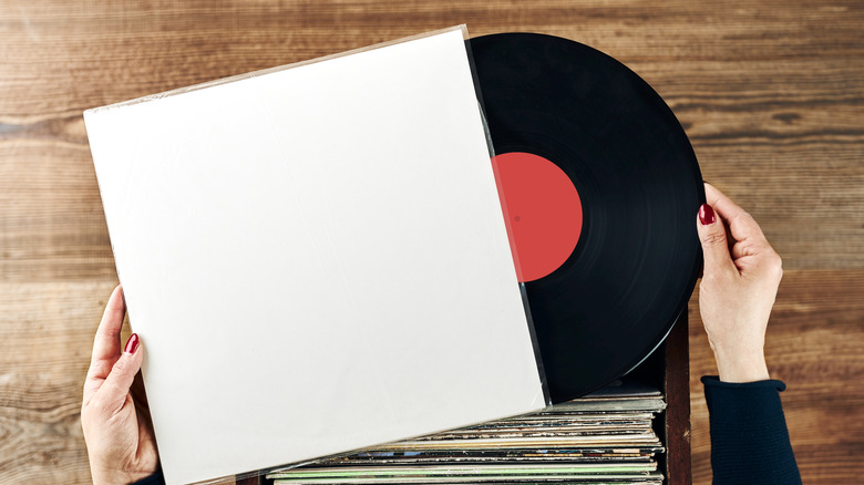 person inspecting vinyl from stack of records