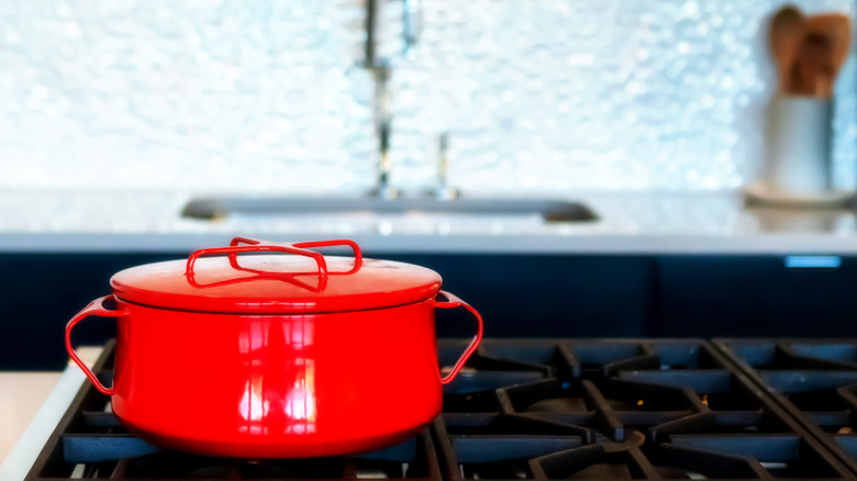 A red Dansk Købenstyle casserole pot on a kitchen stove