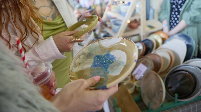 Two women inspecting ceramic plates at a thrift store