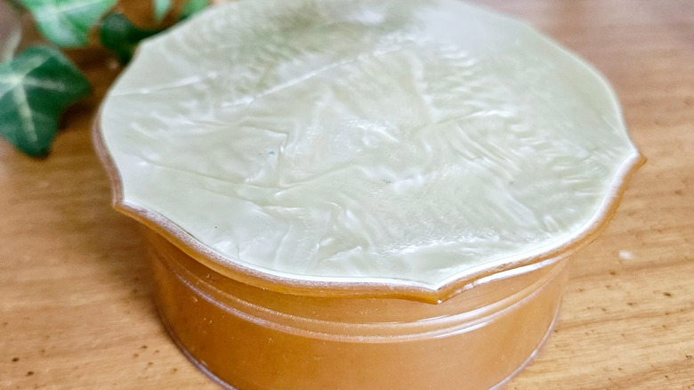 A round, vintage celluloid vanity box with a tan bottom compartment and a white, ivory-like lid