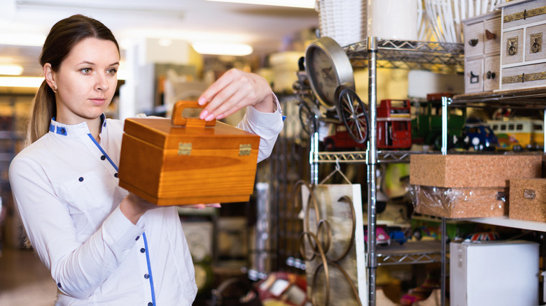 A woman holding a wooden box in a thrift store