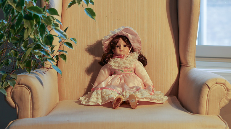 Vintage bisque doll sitting in a chair