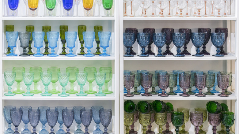 A display of colored glassware on white shelves