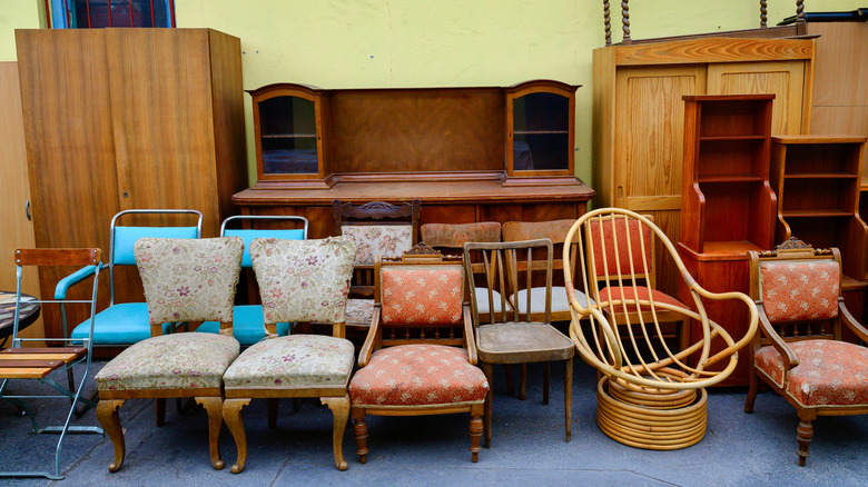 An assortment of wooden and upholstered furniture arranged neatly outside a building.
