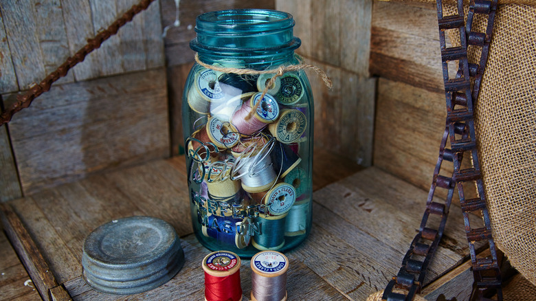Vintage blue glass Ball Mason jar with metal lid filled with spools of thread