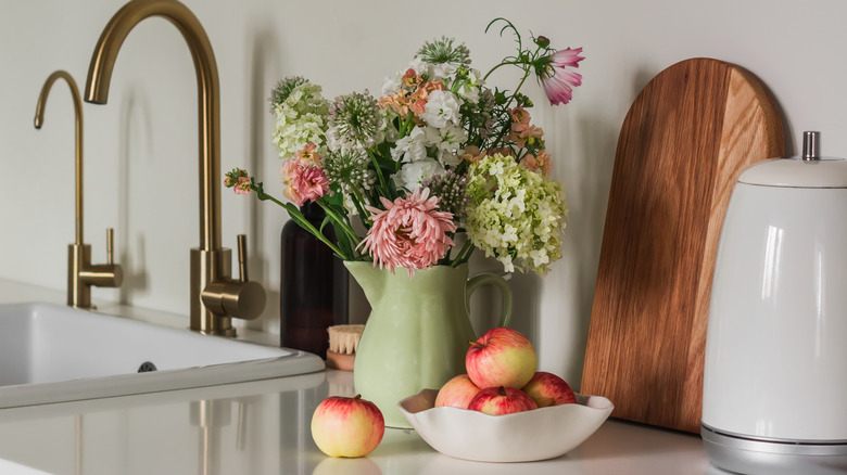 Cut flowers in a vase next to a fruit bowl