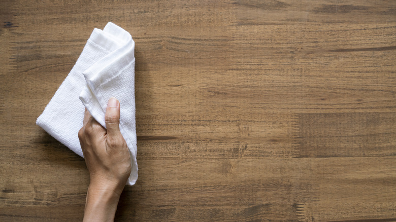 person wiping wood table