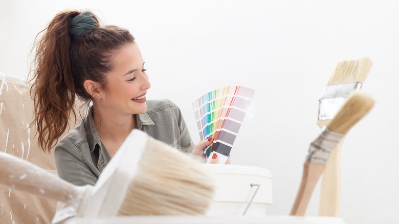 A woman smiles as she looks at paint swatches