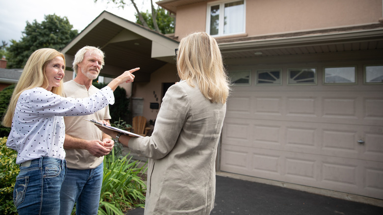 Real estate agent with prospective buyers in front of garage
