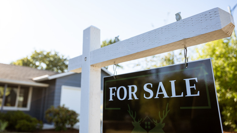 A For Sale sign with home in background