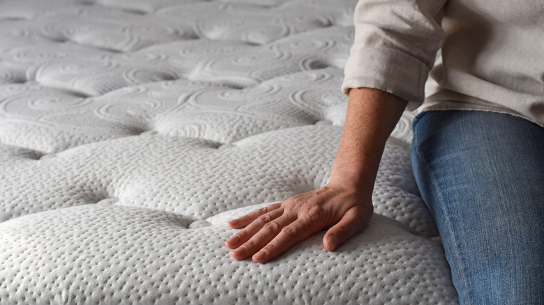 Person in jeans sitting on a bare new mattress