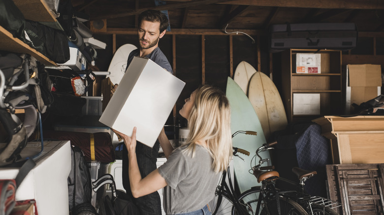 Couple inside garage, putting boxes in shelves
