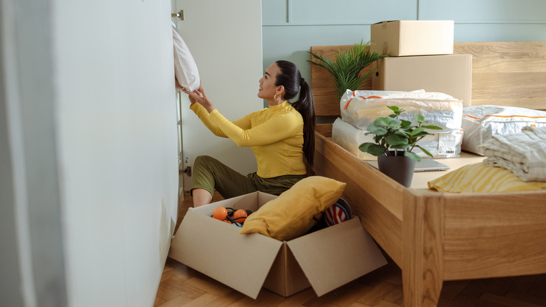 A person decluttering a bedroom and packing away items