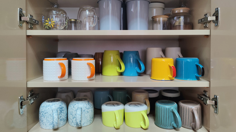 Organized kitchen cabinet filled with colorful mugs