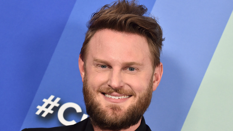 A close up of Bobby Berk's face with a blue to gray background
