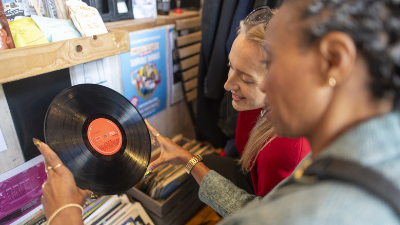 Women shopping at a thrift store going through vinyl records