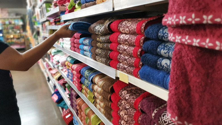 A shopper selecting a towel off a store shelf