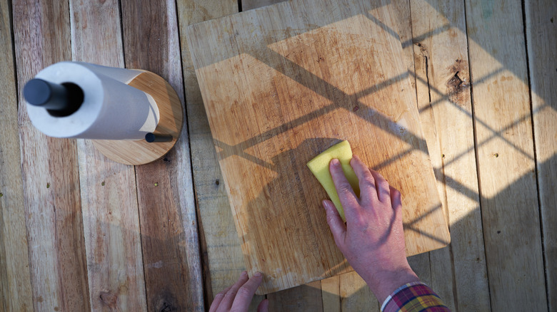 A close up of a hand cleaning stained and damaged wood