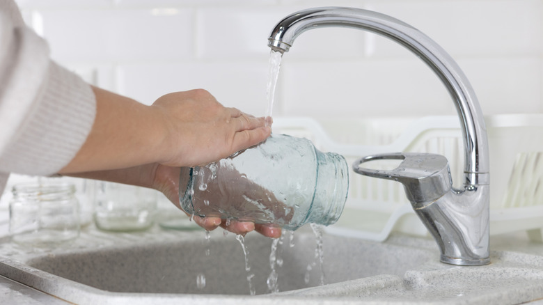 Person rinsing mason jar under the tap