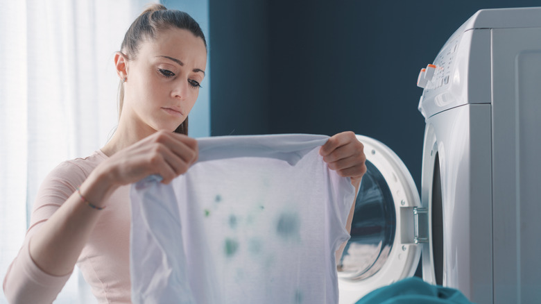Woman looks sadly at a laundry detergent stained shirt.