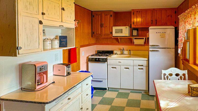 A colorful retro kitchen, equipped with wood cabinets and green checkered tiles