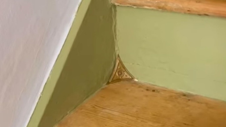 A vintage-inspired brass stair dust corner guard is installed on a modern staircase in a person's home to protect the stair corners from accumulating hard-to-reach dust and debris.