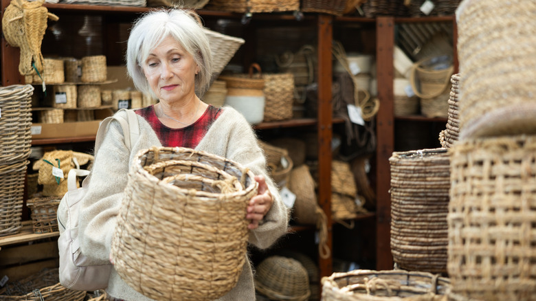 A woman inspecting a wicker basket in a store.